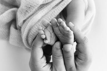 Children's foot in the hands of mother, father, parents. Feet of a tiny newborn close up. Little...