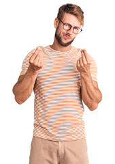 Young caucasian man wearing casual clothes and glasses doing money gesture with hands, asking for...
