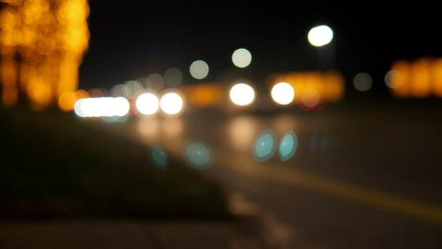 A blurry image of cars on the road with garlanded trees. Bokeh. City road with golden flashing lights. The trees are covered with many golden lights in the evening.
