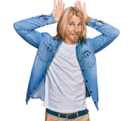 Caucasian man with blond long hair wearing casual denim jacket doing bunny ears gesture with hands palms looking cynical and skeptical. easter rabbit concept.
