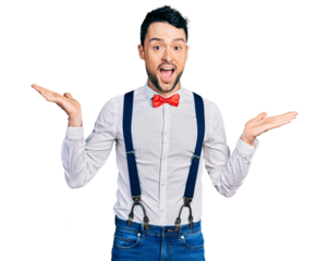 Hispanic man with beard wearing hipster look with bow tie and suspenders celebrating crazy and amazed for success with arms raised and open eyes screaming excited. winner concept