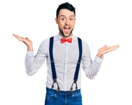 Hispanic man with beard wearing hipster look with bow tie and suspenders celebrating crazy and amazed for success with arms raised and open eyes screaming excited. winner concept - Powered by Adobe