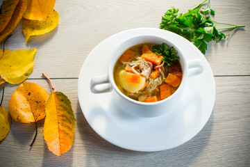 Autumn soup with chicken, noodles and autumn vegetables in a bowl .