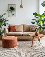 Beige velvet sofa with terra cotta cushions between houseplants Wooden round coffee table