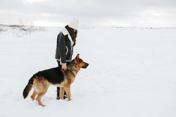 Young woman walk the dog German Shepherd in winter field forest, running playing with snow, training the animal in harsh conditions, wind blowing. Christmas Time, New Year
