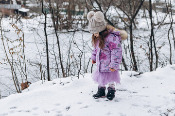 Little girl child walking alone in winter forest city park having fun spending time, wintertime christmas atmosphere
