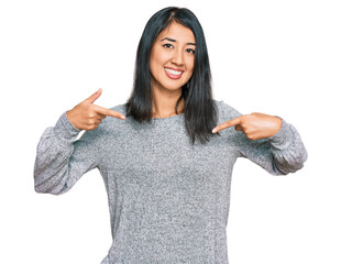Beautiful asian young woman wearing casual clothes looking confident with smile on face, pointing...