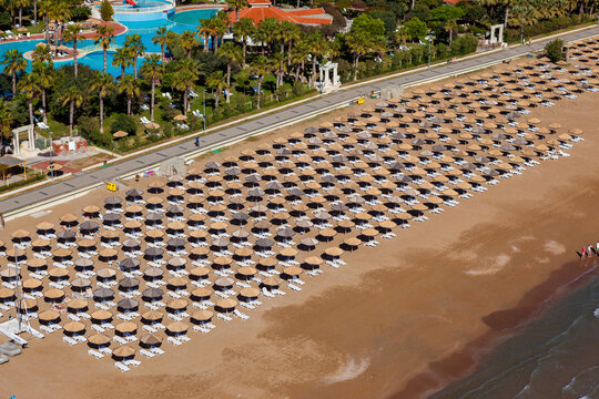 Aerial view rows of umbrellas and chairs on a beach on the Mediterranean Sea coast of Belek, Antalya, Turkey.