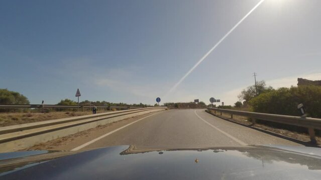 First person view, FPV, from dashcam of car driving along the Algarve Coast in Portugal outside of Portimao towards the Benagil Caves, driving on the highway. Road trip video in POV, with blue sky