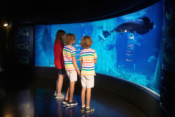 Family in aquarium. Kids watch fish, marine life