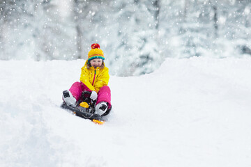 Girl on sled ride. Child sledding. Kid on sledge