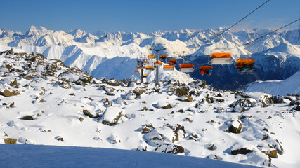 Orange chairlift with unrecognizable skiers in Samnaun - Ischgl - Paznaun ski resort, located in...