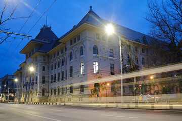Bucharest town hall building exterior with car trail at twilight. Administration landmark in Romania capital city. - obrazy, fototapety, plakaty