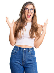 Obraz na płótnie Canvas Beautiful caucasian young woman wearing casual clothes and glasses crazy and mad shouting and yelling with aggressive expression and arms raised. frustration concept.