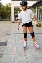 Roller skating girl in park, rollerblading. Child in outdoor activities.