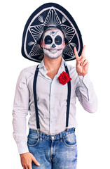 Man wearing day of the dead costume over background showing and pointing up with fingers number two while smiling confident and happy.