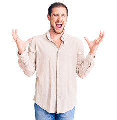 Young handsome caucasian man wearing casual clothes crazy and mad shouting and yelling with aggressive expression and arms raised. frustration concept.