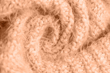 Peach fuzz, color of the year 2024, knitwear texture. Soft texture of homemade cashmere wool sweater toned on peach fuzz color.