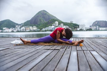 Poster Mulher de meia idade se alongando, praticando ioga, sentada em um pier a beira da lagoa no Rio de Janeiro. © Brastock Images