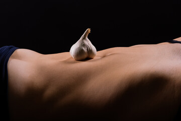 Close up of woman belly with laying garlic, low key
