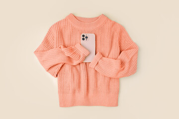 Knitted orange sweater with smartphone. Peach Fuzz - color of the year 2024. Women's warm jumper,...