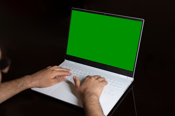 An isolated image on the black background of a white simple slim and gaming laptop with green...