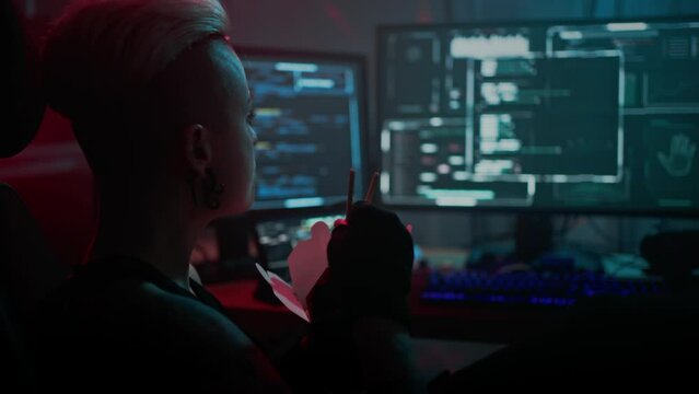 Female coder enjoys noodles checking program on monitors