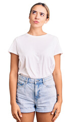Obraz premium Young beautiful blonde woman wearing casual white tshirt smiling looking to the side and staring away thinking.