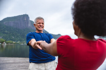 Middle-aged man holding hands with his partner on a pier at the edge of the lagoon. Point of view.