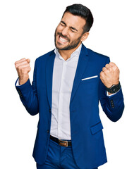 Young hispanic man wearing business jacket very happy and excited doing winner gesture with arms...