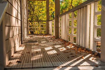 A cozy wooden house with autumn foliage and shadows - obrazy, fototapety, plakaty