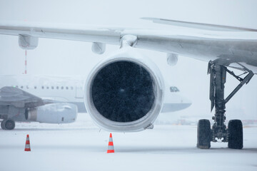 Traffic at airport during heavy snowfall. Snowflakes against jet engine and taxiing airplane at...