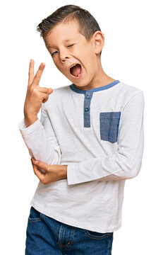 Adorable caucasian kid wearing casual clothes smiling with happy face winking at the camera doing victory sign. number two.