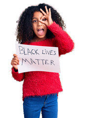 African american child with curly hair holding black lives matter banner smiling happy doing ok...