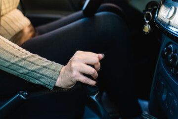Close-up of an unrecognizable woman's hand changing the gear of her car with the gearshift lever...