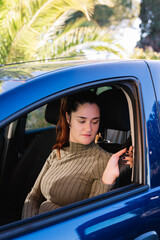 Portrait of young woman driver holding the seat belt in her car. Concept of road safety