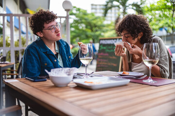 Couple of women eating and having fun during pleasant lunch in an open-air restaurant.