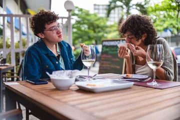 Fotobehang Couple of women eating and having fun during pleasant lunch in an open-air restaurant. © Brastock Images