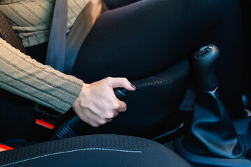 Close-up of a young woman driver's hand using the handbrake of her car. Driving concept