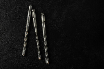 Three drills made of hard material for concrete on a black background.