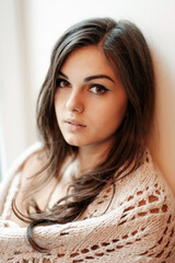 Close up emotional portrait of a beautiful young brunette woman with long hair looking to the camera