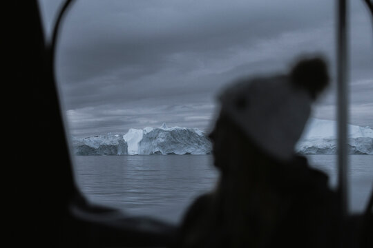 View of persons on a boat watching icebergs at disco bay ice fjord in Ilulissat, Greenland.