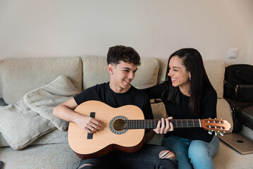 Cheerful couple with guitar on sofa at home