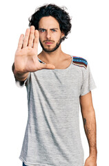 Fototapeta premium Young hispanic man wearing casual t shirt doing stop sing with palm of the hand. warning expression with negative and serious gesture on the face.