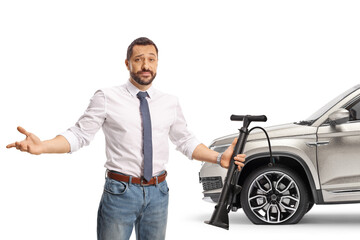 Obraz premium Man holding a manual tire pump in front of a car with flat tire