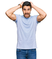 Fototapeta premium Young hispanic man wearing casual clothes crazy and scared with hands on head, afraid and surprised of shock with open mouth
