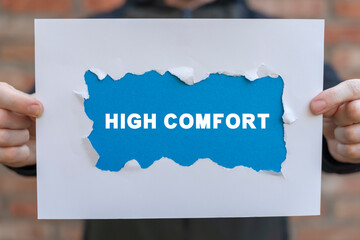 Man holding white and blue sheets of paper with inscription: HIGH COMFORT. Concept of achievement...