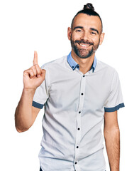 Hispanic man with ponytail wearing casual white shirt showing and pointing up with finger number...