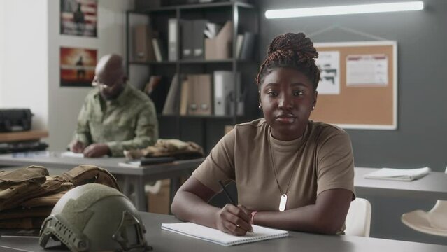 Medium portrait of female African American cadet studying during class and then looking at camera in military academy