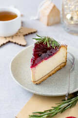A piece of cheesecake with berry sauce on a plate with a cup of tea. Cheesecake in a New Year's composition.